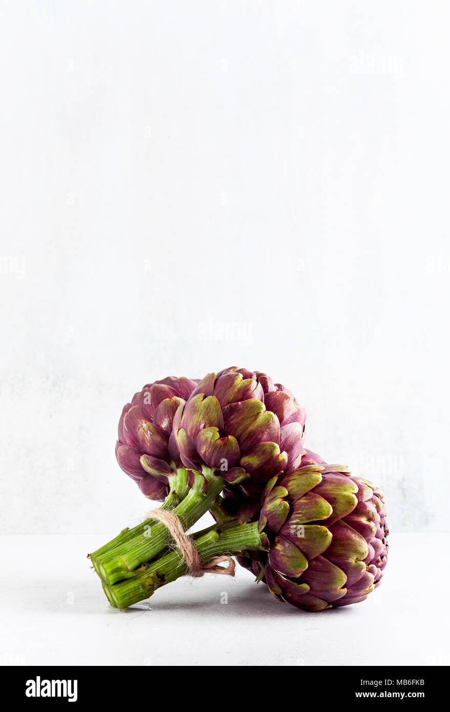Frisches Bündel lila Artischocken auf weißem Hintergrund. Feder, gesundes Essen mit Kopie Raum Stockfoto