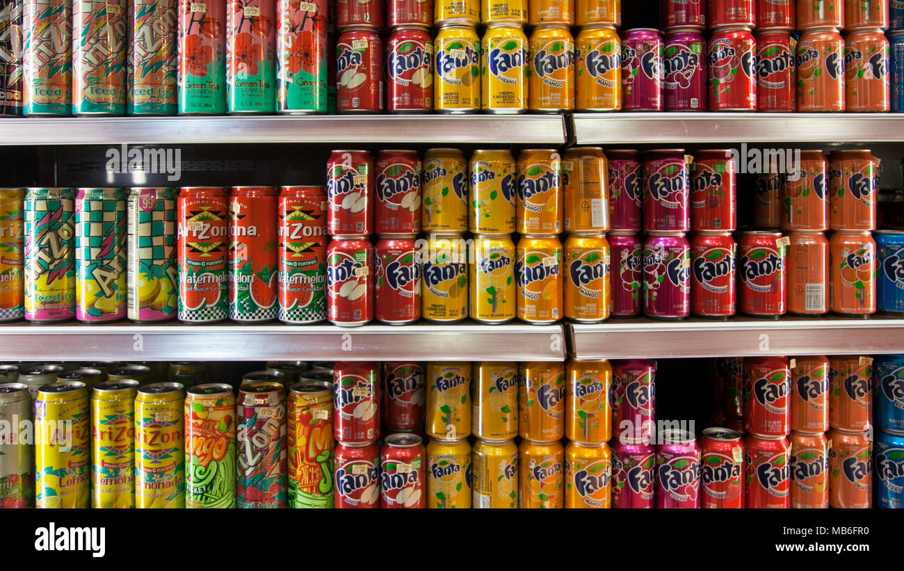 Gekühlte Dosen von alkoholfreien Getränken, gestapelte Regale mit Sodagetränken, Getränken, Erfrischungen, kalten, süßen, Flüssige, Süßwaren & Süßwaren zuckerhaltige Produkte unterliegen jetzt der Zuckersteuer, um Fettleibigkeit in einem Kühlvitrine zu kontrollieren. Stockfoto