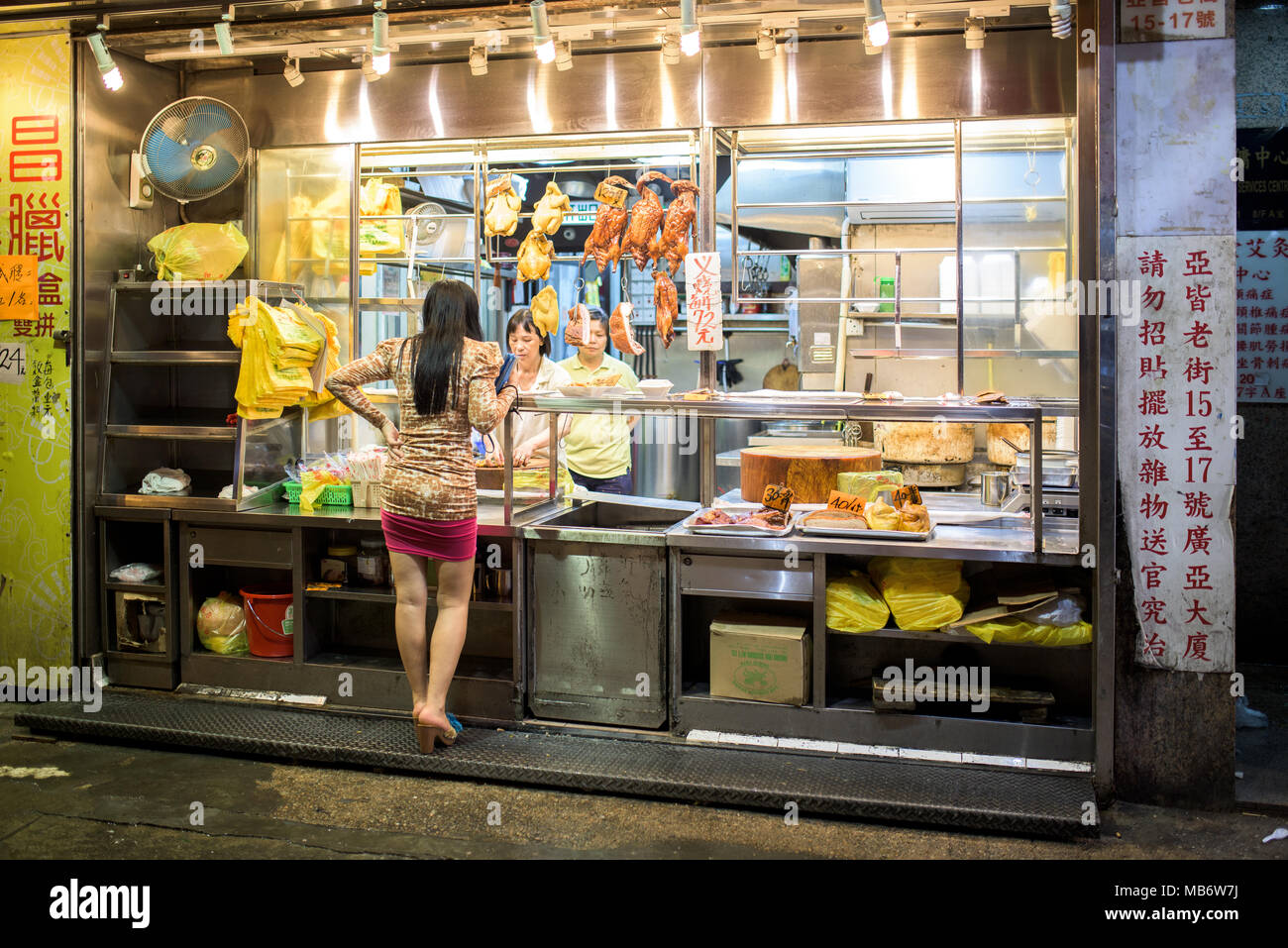 Chinesische Frau vor dem Essen Shop in den Straßen von Hong Kong Stockfoto