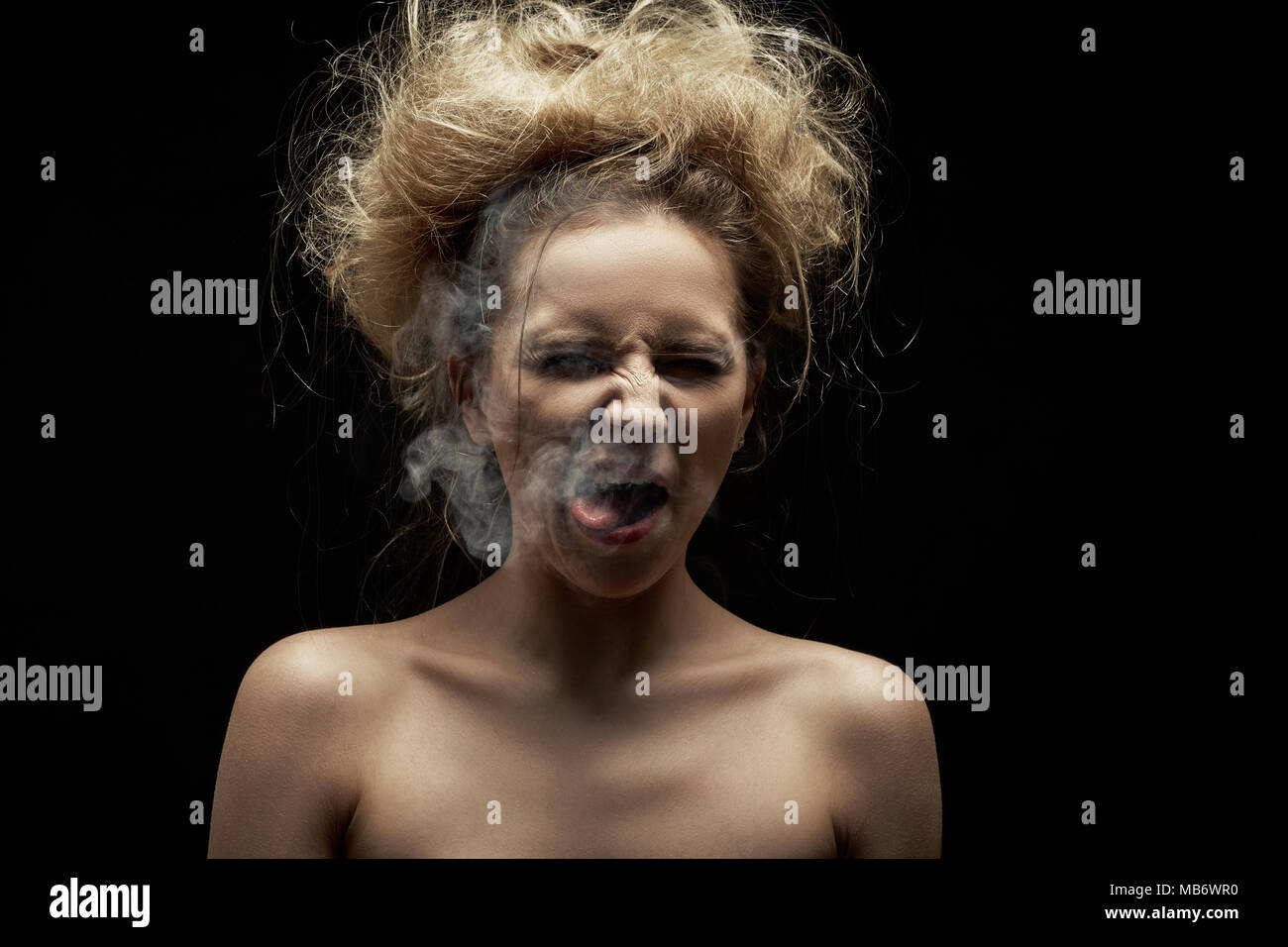 Mädchen Husten von Tabakrauch auf schwarzem Hintergrund Stockfoto
