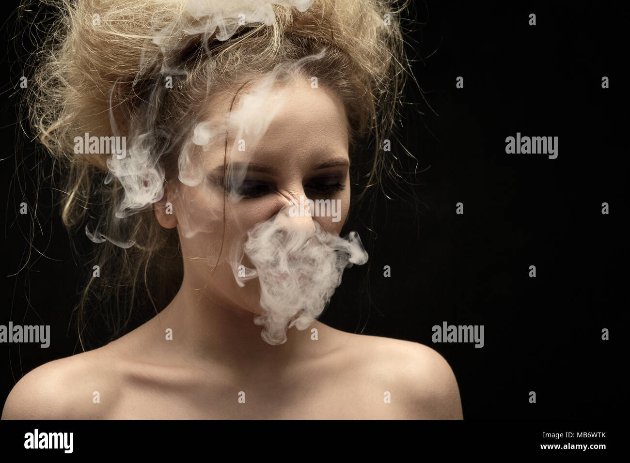 Mädchen Husten von Tabakrauch auf schwarzem Hintergrund Stockfoto
