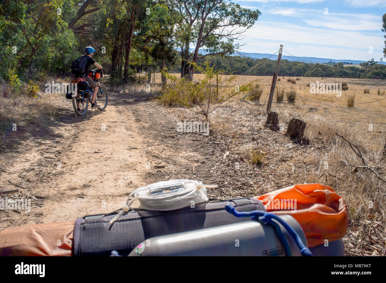 Ein junger Mann Pausen für eine Pause während einer Bike-verpackung Abenteuer in Australien. Stockfoto