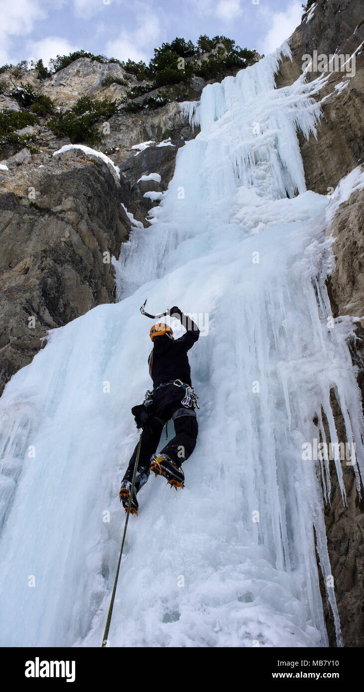 Männliche Eiskletterer auf einem steilen gefrorenen Wasserfall an einem schönen Wintertag in den Schweizer Alpen Stockfoto