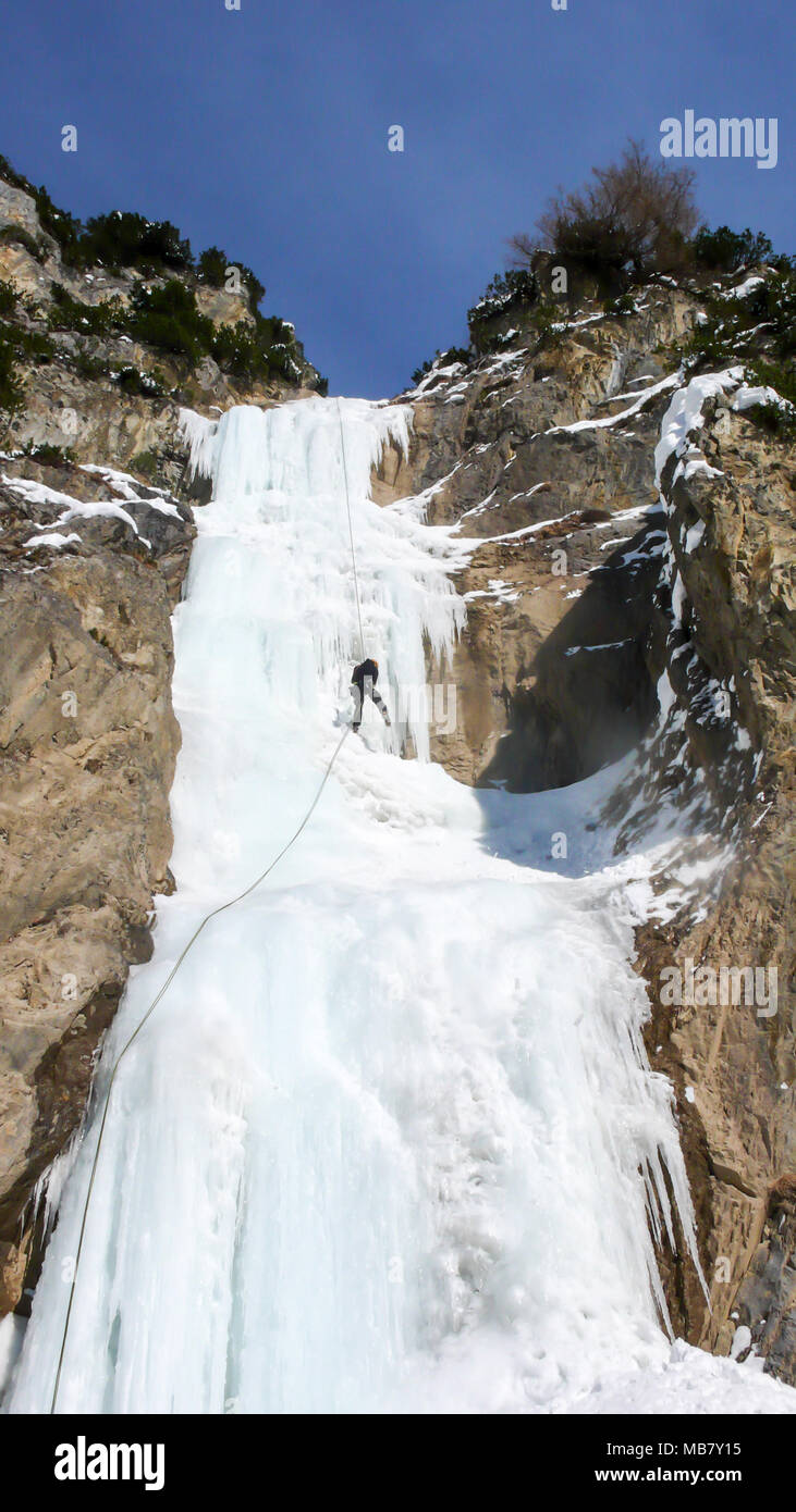 Männliche Bergführer Abseilen aus einem steilen gefrorenen Wasserfall nach einem ice Ausflug klettern Stockfoto