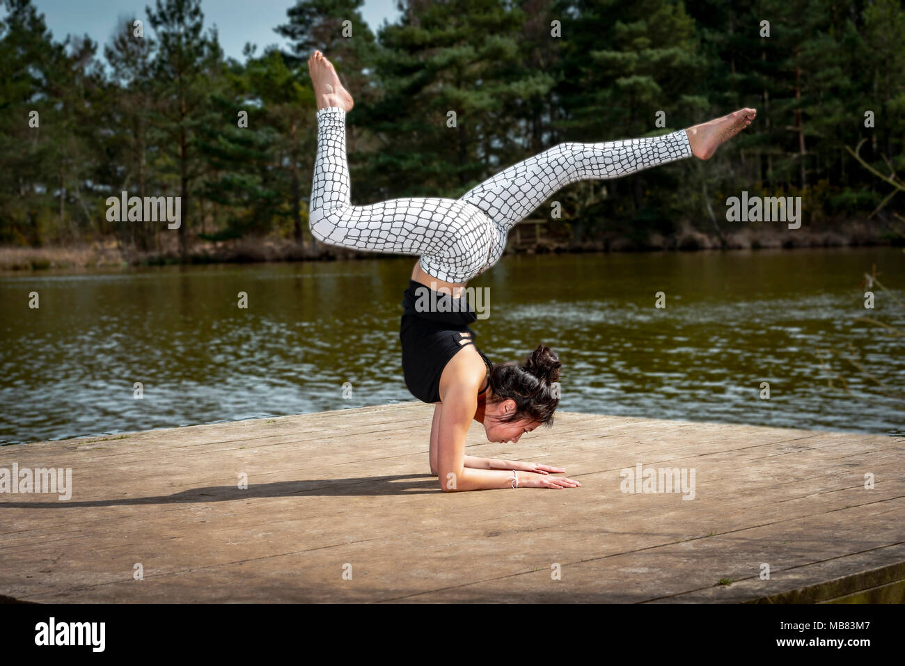 Frau Yoga am See tun ein kniestück Balance. Stockfoto