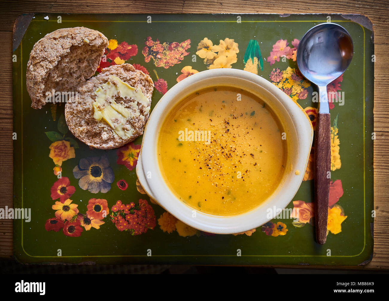 Ein rustikales Schüssel dicke Suppe und Löffel mit einem Gebutterten vollkorn Brötchen Stockfoto