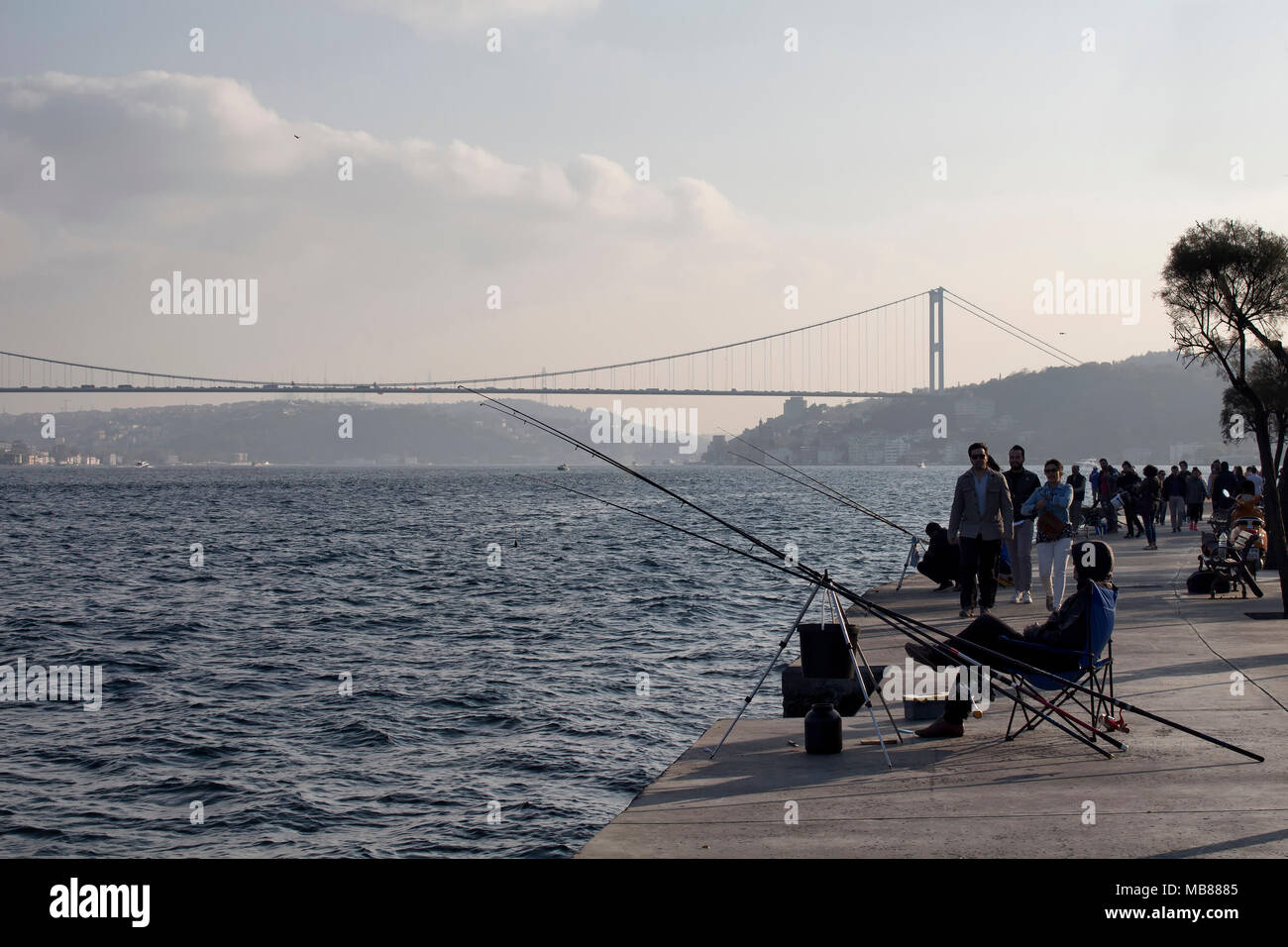 Menschen gehen und Fischer fangen Fische durch den Bosporus in Istanbul. FSM Brücke im Hintergrund Stockfoto