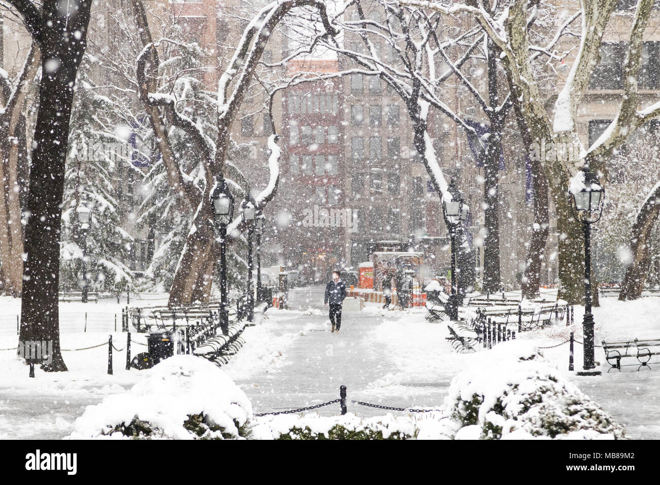 Mann zu Fuß durch eine verschneite Landschaft Blizzard in den Washington Square Park, New York City Stockfoto