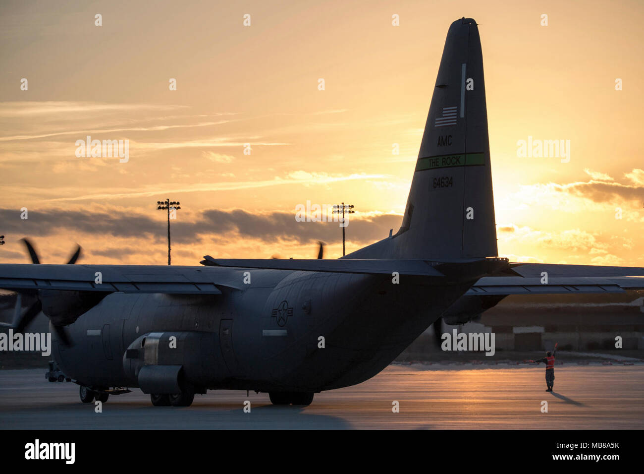 Papst Army Airfield, N.C. - Eine C-130 J Hercules aus dem 19 Airlift Wing an Little Rock Air Force Base, Arche, bereitet mit einer Last der 82nd Airborne Division Fallschirmjäger bei Sonnenuntergang auf Grün Rampe hier zu starten, Feb 9, 2018 als Flieger vom 43 d Air Mobility Squadron an Papst Marshalls ein anderes Luftfahrzeug von seinem Parkplatz bei einer gemeinsamen großen Paket Woche und Not der Bereitstellungsbereitschaft Übung Feb. 5-11. Flieger in den 43 d Air Mobility Operations Group bei Papst mitgeführte Unterstützung für den Besuch von Air Force Piloten ihren Hilfsfluegen Soldaten und Ausrüstung aus Papst Feld während der Übung. Stockfoto