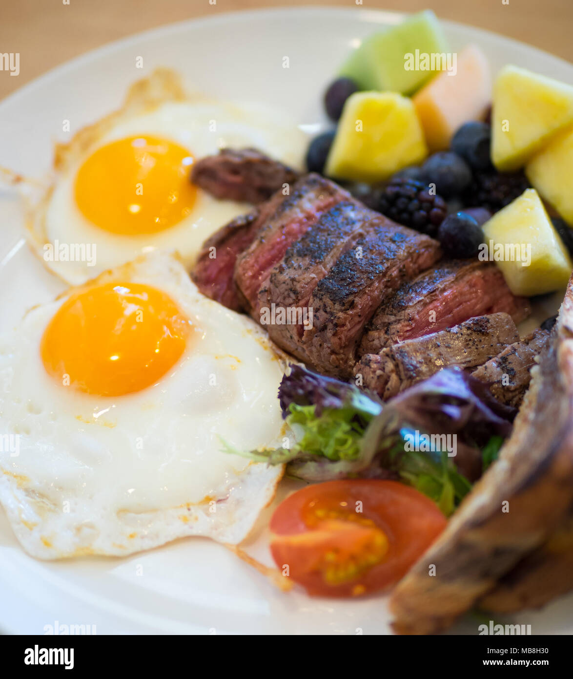 Steak Eier zum Frühstück in der Heimatstadt Diner in Saskatoon, Kanada. Medium Flank Steak, Spiegeleier, Marmor Roggen Toast und Früchte abgebildet. Stockfoto