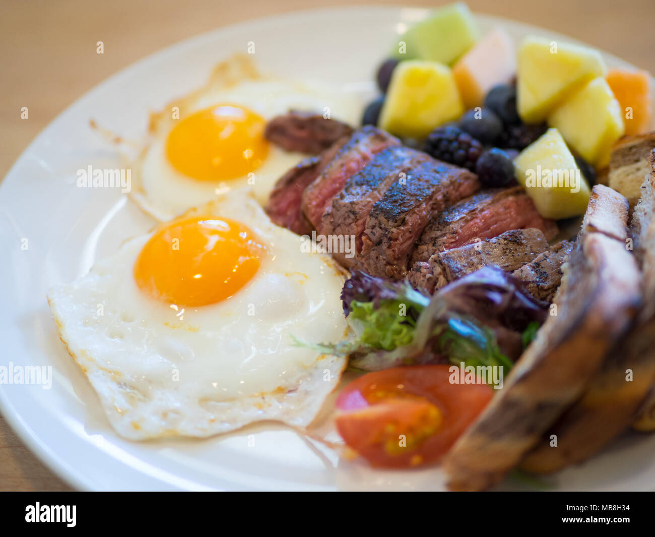 Steak Eier zum Frühstück in der Heimatstadt Diner in Saskatoon, Kanada. Medium Flank Steak, Spiegeleier, Marmor Roggen Toast und Früchte abgebildet. Stockfoto
