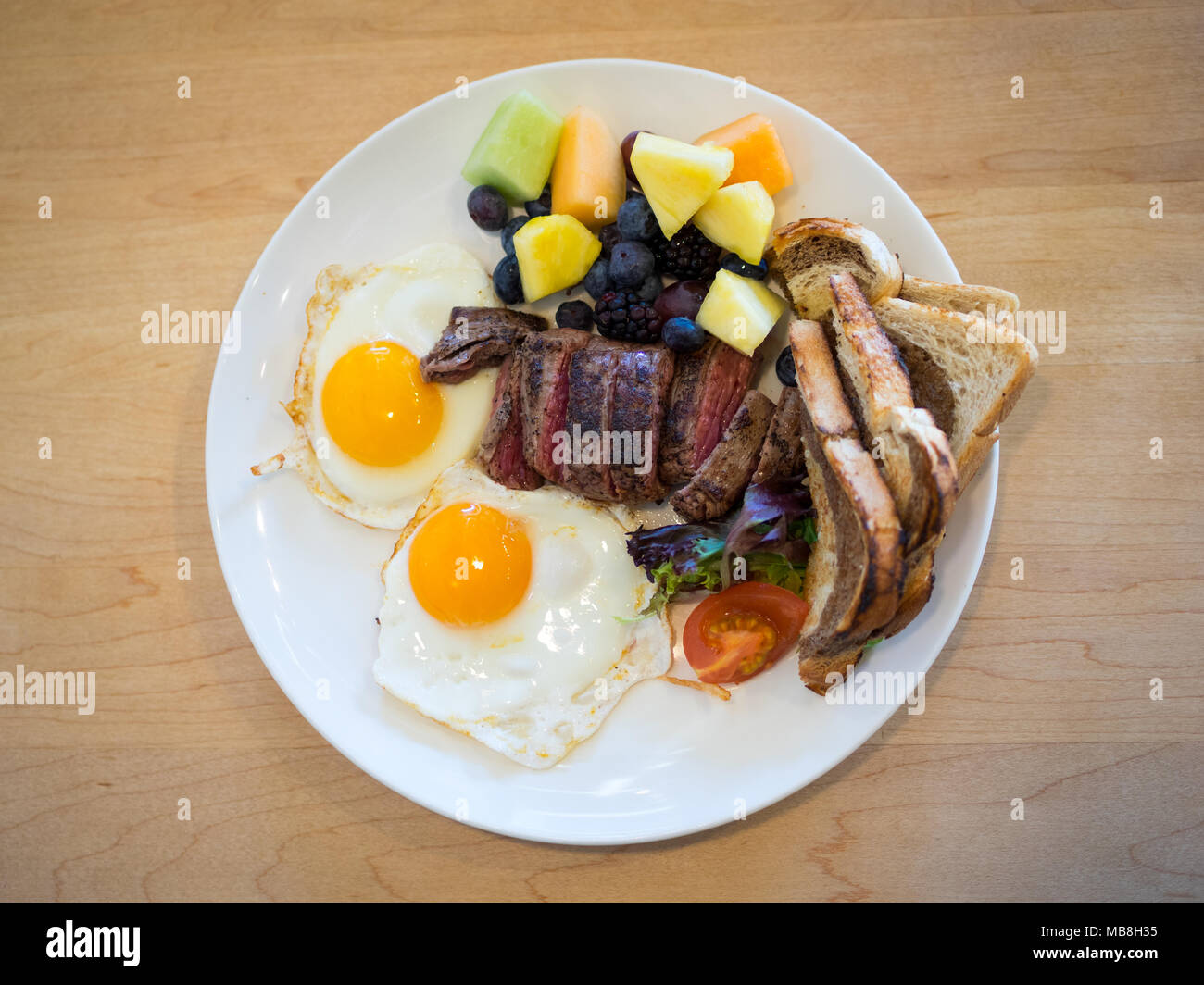 Steak Eier zum Frühstück in der Heimatstadt Diner in Saskatoon, Kanada. Medium Flank Steak, Spiegeleier, Marmor Roggen Toast und Früchte abgebildet. Stockfoto