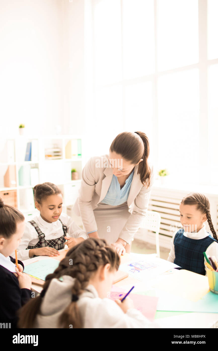 Lehrer unterrichten die Kinder im Unterricht in der Schule. Sie sitzen zusammen am Tisch und Zeichnung Stockfoto