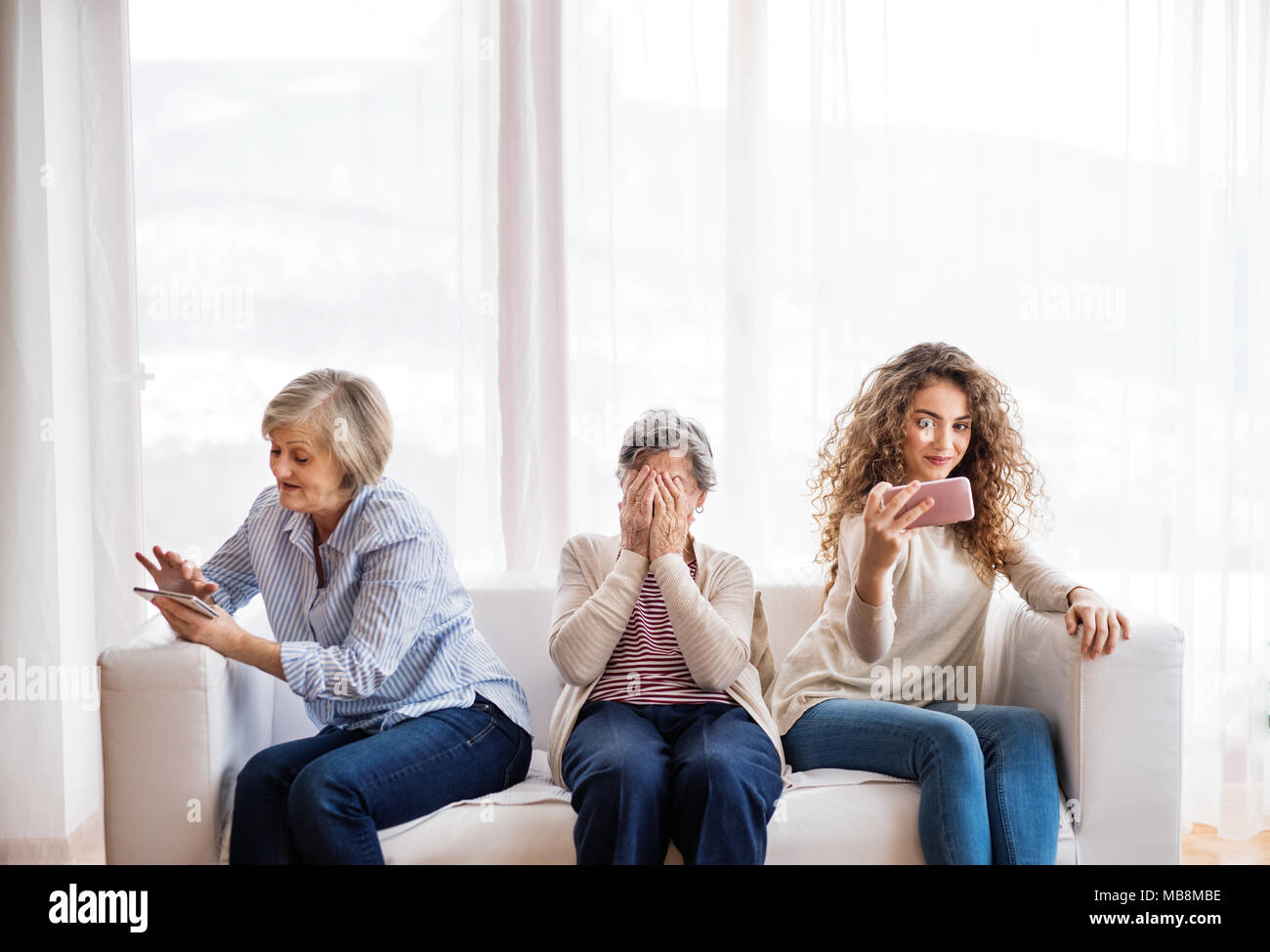 Ein junges Mädchen, Mutter und Großmutter mit Smartphone zu Hause. Stockfoto