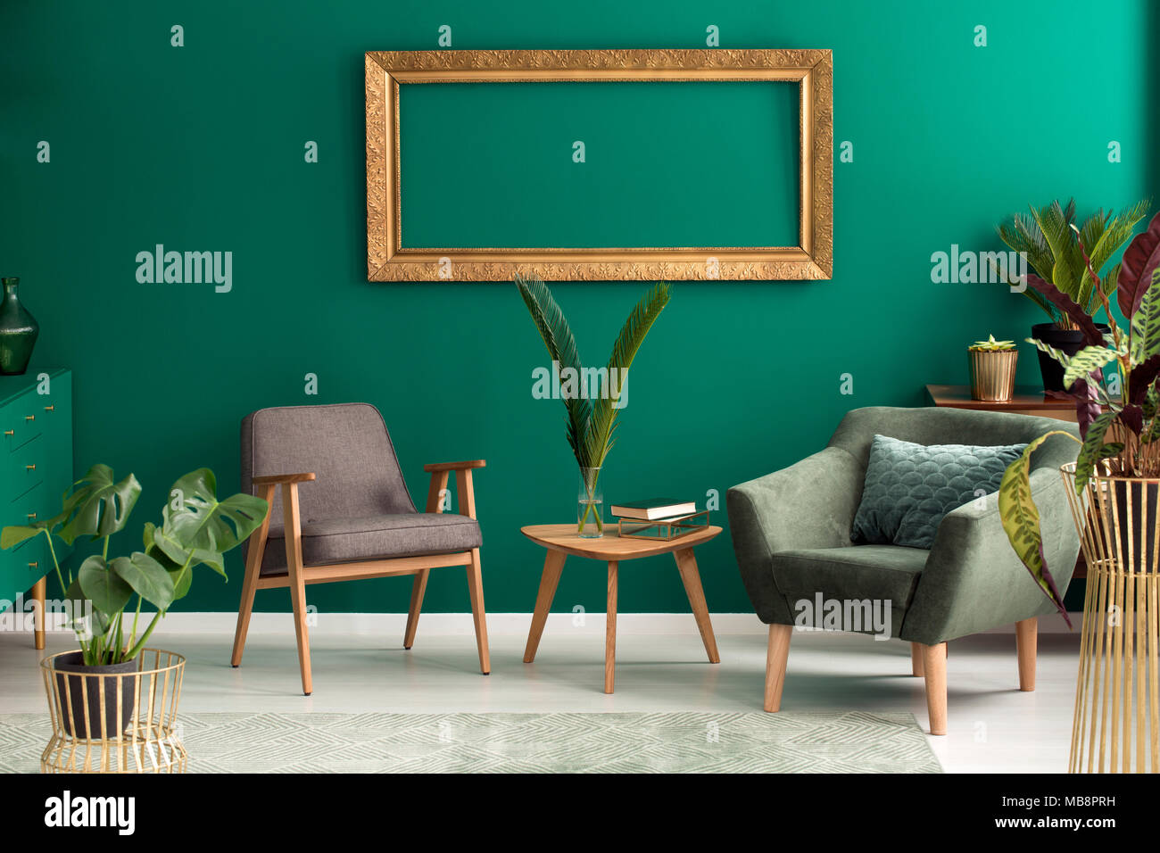 Leer, gold Rahmen auf der Wand über Grau und Grün Sessel im Wohnzimmer Innenraum Stockfoto