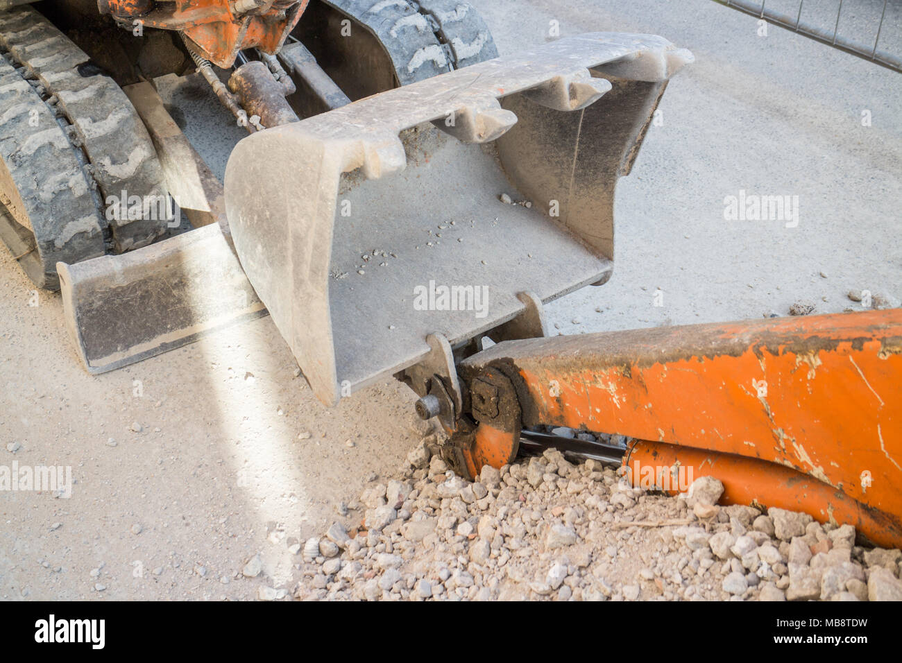 Kleine orange Bagger und Geröll auf der Straße, Bürgersteig Bau Stockfoto