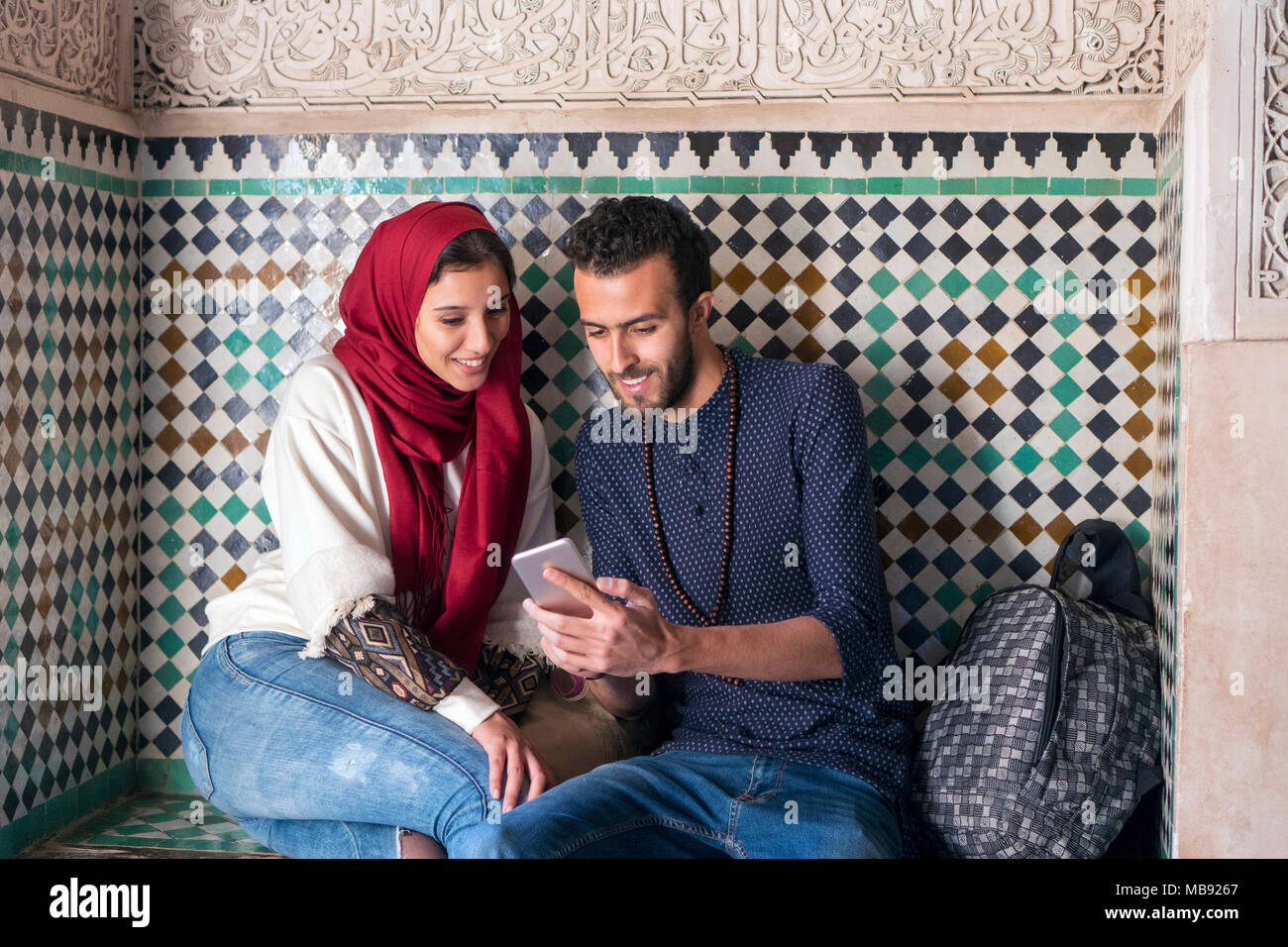 Junge muslimische Paar lächelnd und Mobiltelefon Stockfoto