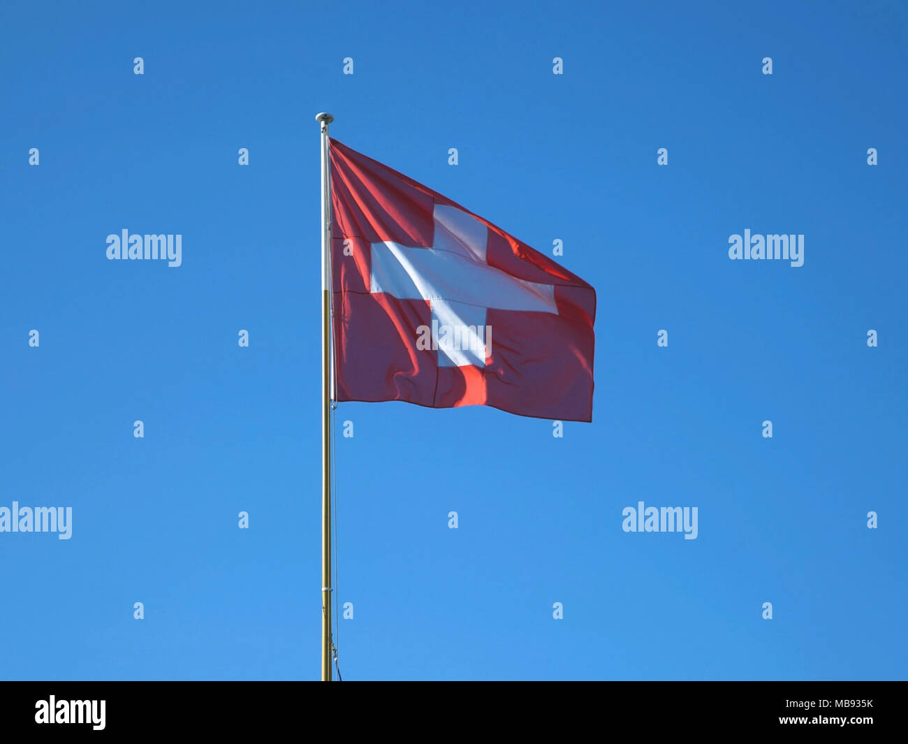 Schweizer Flagge weht im Wind auf einem Fahnenmast Stockfoto