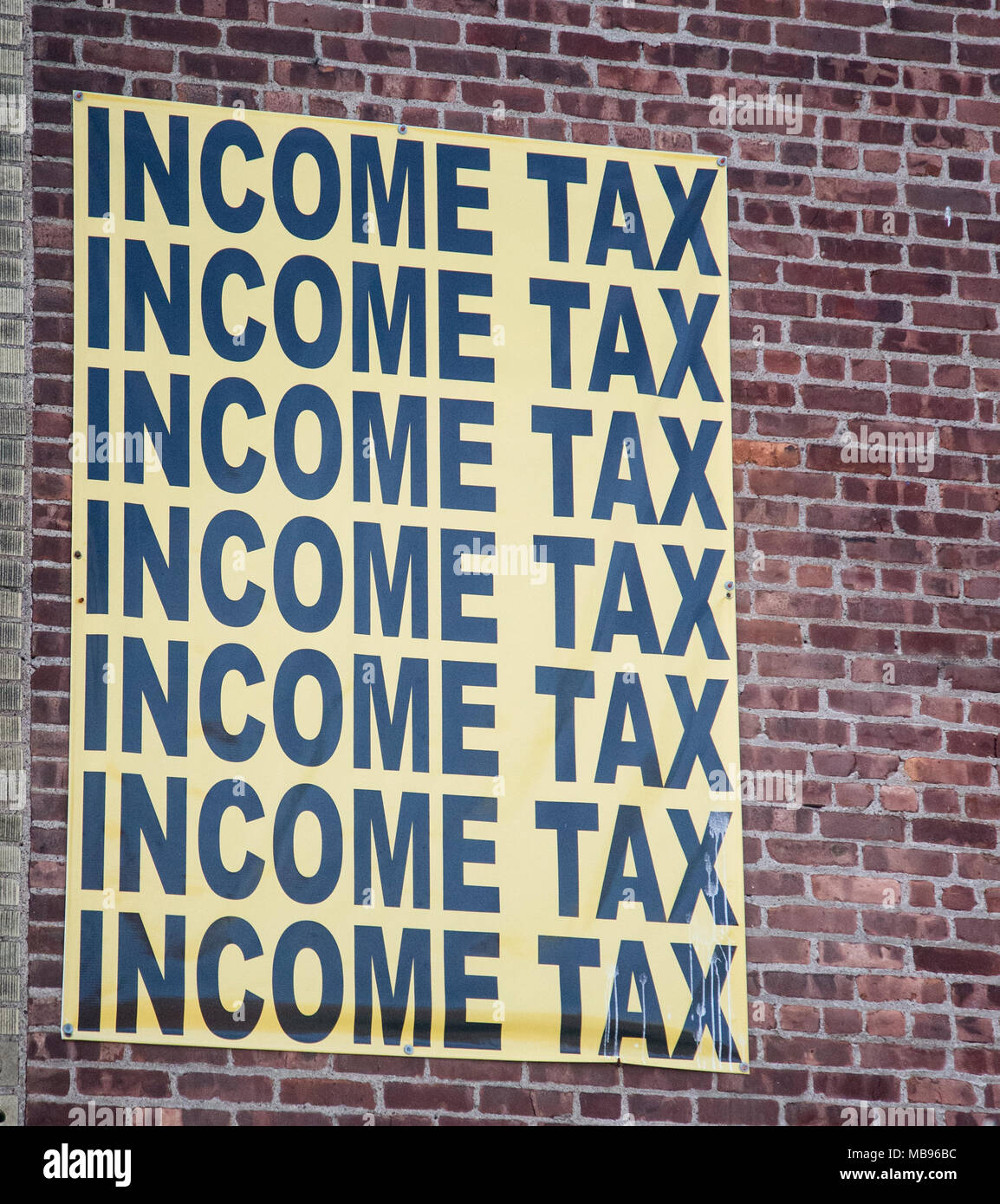 Steuern vom Einkommen und Zeichen auf der Seite eines Gebäudes in Paterson, NJ Stockfoto