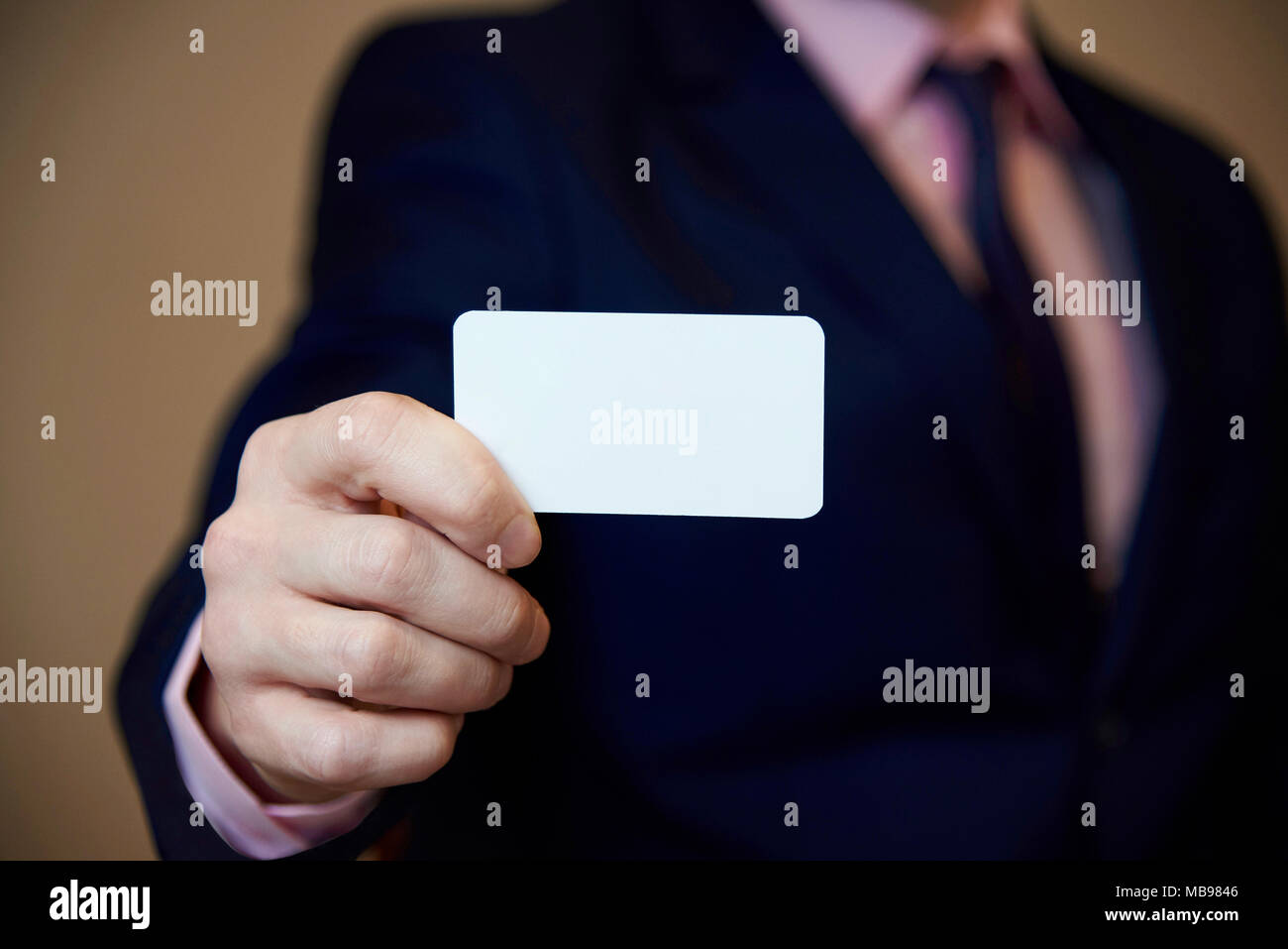Eine weiße Leere Visitenkarte in der Hand, ein junger Mann im Anzug. Stockfoto