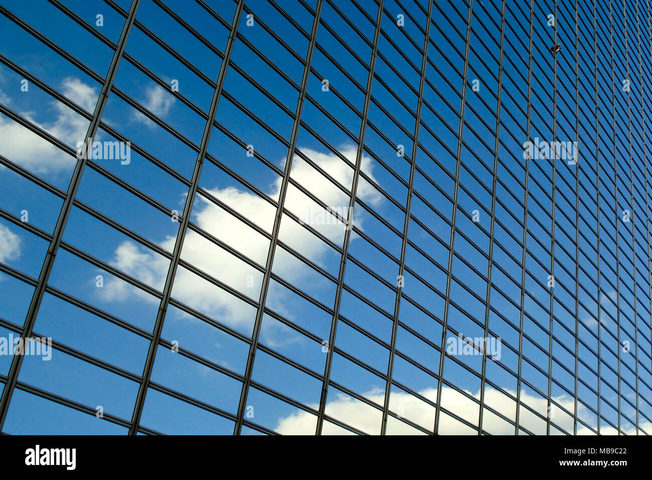 Blauer Himmel mit Wolken Reflexionen über eine moderne Glas Geschäft Gebäude Stockfoto