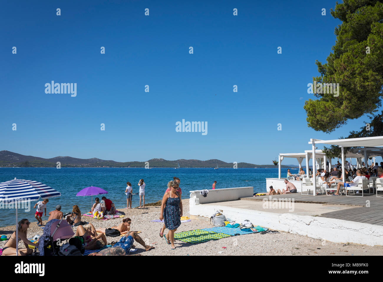 Sonne bräunen Menschen am Strand von Zadar, mit einem Cafe Terrasse an der Seite, Kroatien Stockfoto