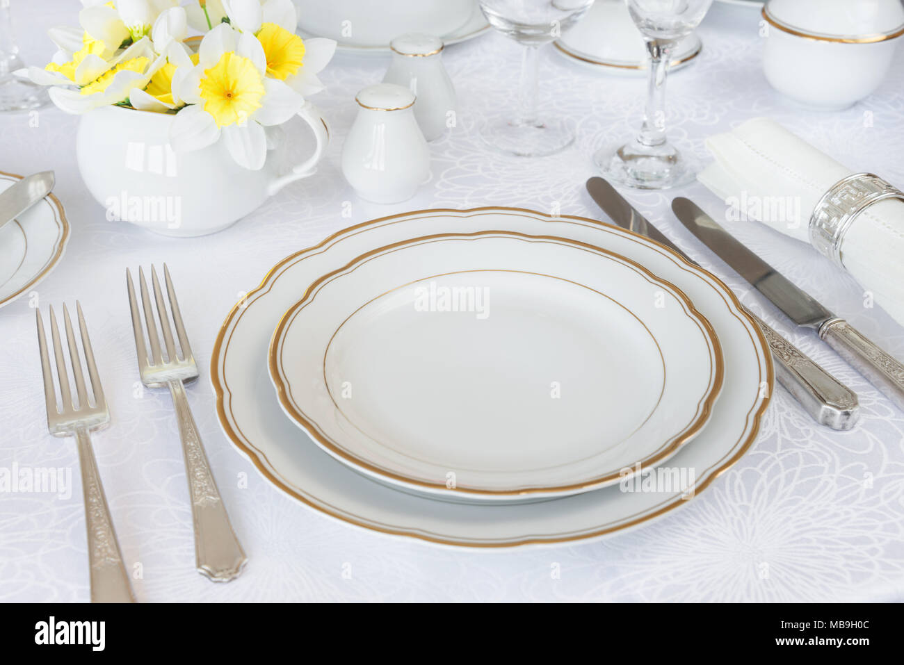 Classic für ein Galadinner mit luxuriösen Porzellan, Silberbesteck und Frühling Blumen auf einem weißen Tischtuch Stockfoto