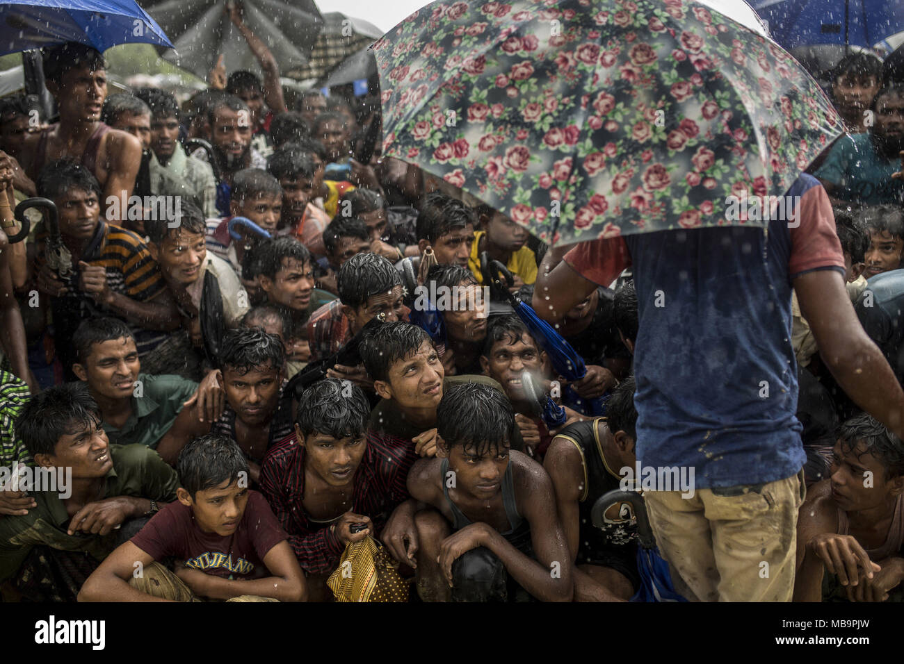 Coxs Bazar, Bangladesch. 28 Sep, 2017. Dutzende Männer warten im Regen für etwas in der Balukhali Flüchtlingslager zu essen. verschiedene NGOs essen täglich verteilen, aber es gibt so viele Menschen, die in einigen Orten gibt es große Warteschlangen. Bangladeshi Soldaten und freiwilligen Kontrolle, dass Niemand überspringt die Umdrehung zwingen, die Flüchtlinge zu sitzen bleiben. 9/26/2017. Credit: Olmo Calvo/ZUMA Draht/Alamy leben Nachrichten Stockfoto