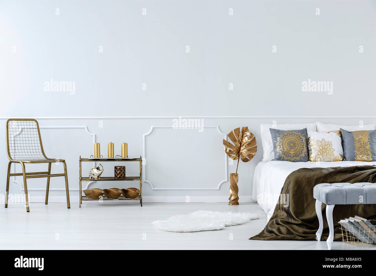 Goldene Stuhl, Regal und einem Doppelbett in Weiß Schlafzimmer Innenraum mit Wand spritzgießen Stockfoto
