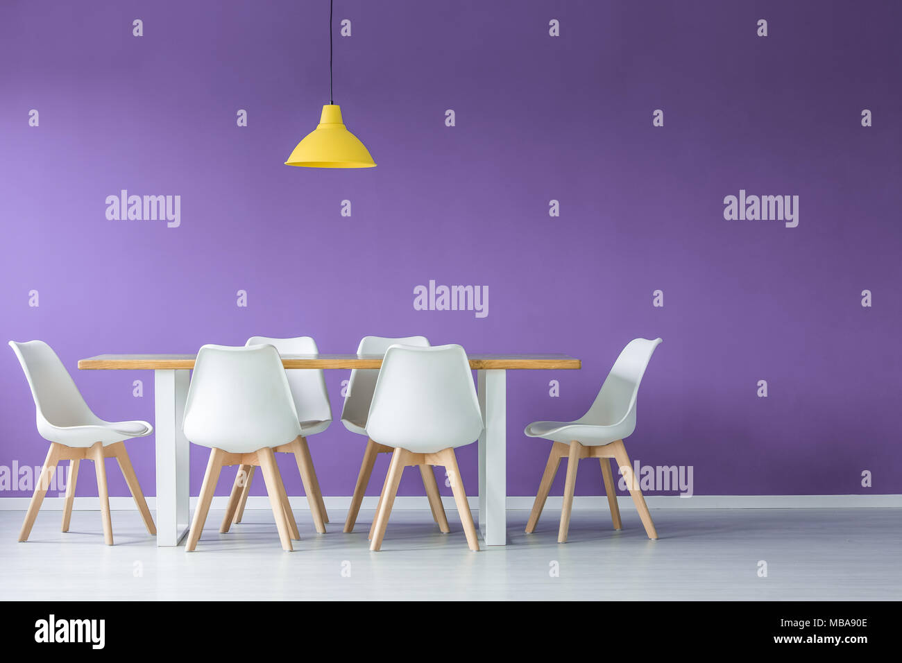 Einfache Und Moderne Einrichtung Mit Weissen Open Space Und Stuhle Aus Holz Um Einen Esstisch Und Gelbe Lampe Gegen Lila Wand Stockfotografie Alamy