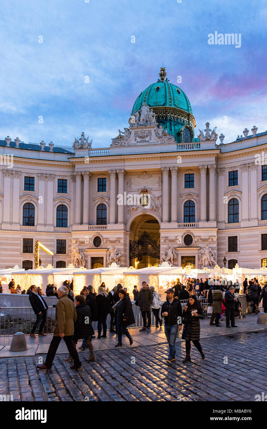 K.u.K. (Kaiserliche und Königliche) Weihnachtsmarkt am Michaelerplatz vor dem Kaiserlichen Palast und viele Leute gehen um Stockfoto