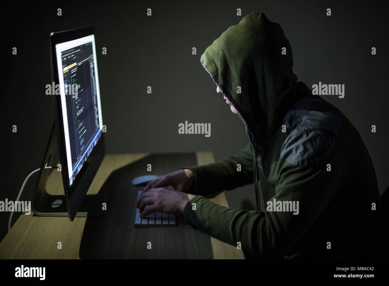 Computer Hacker in der Motorhaube in dunklen Raum arbeiten Stockfoto