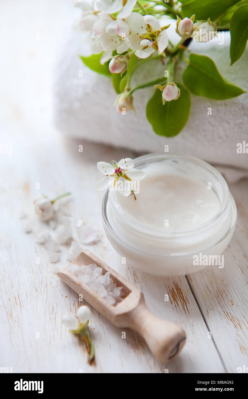 Haut Creme und schöner Frühling white flower auf weiße Holztisch Topf beauty Creme umgeben von Blumen und Meersalz Stockfoto