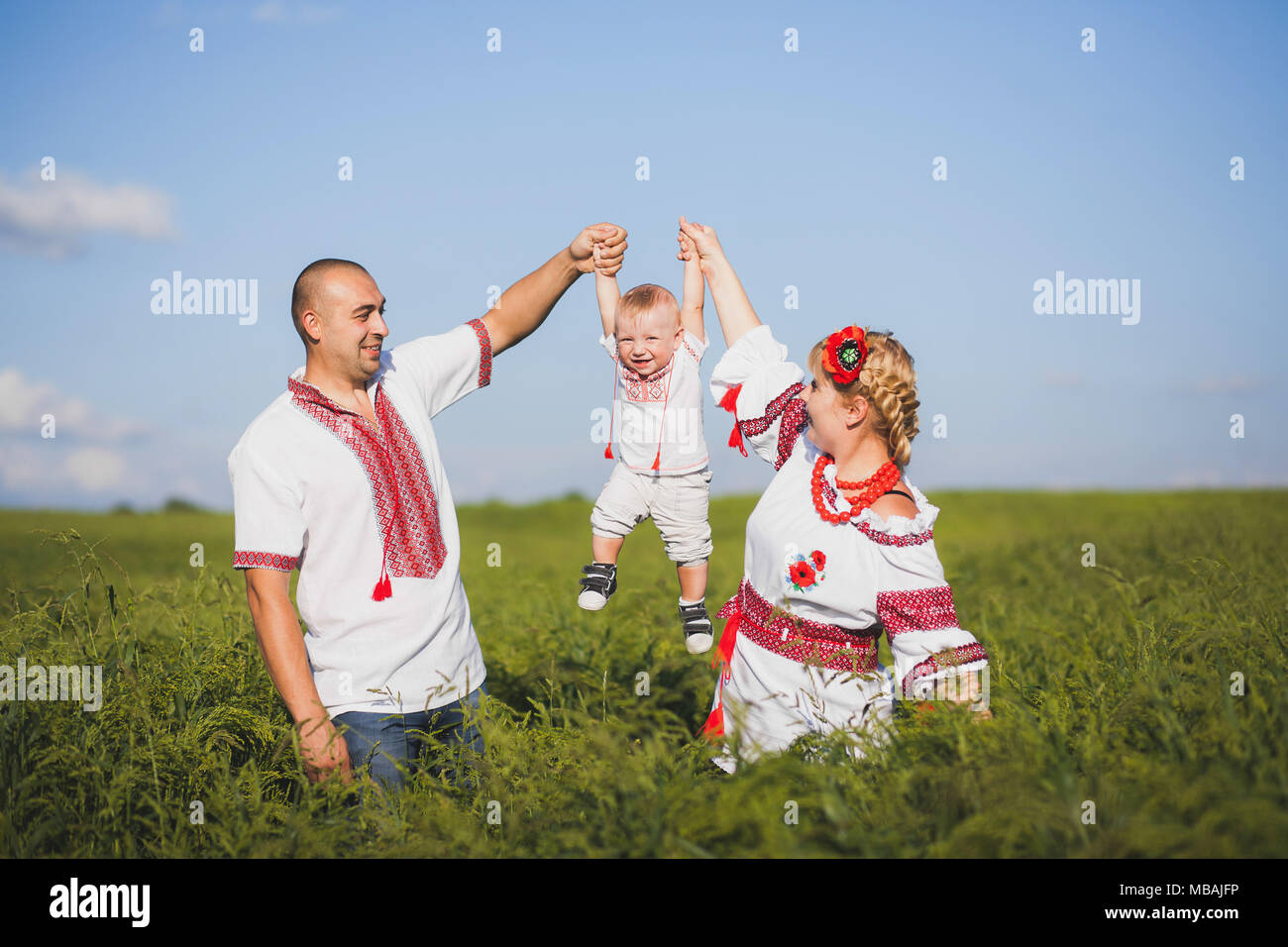 Portrait von ethnischen ukrainische Familie tragen traditionelle weiße Kleidung. Vater, Mutter und Baby Spaß draußen im Sommer Sonnig. Horizo Stockfoto
