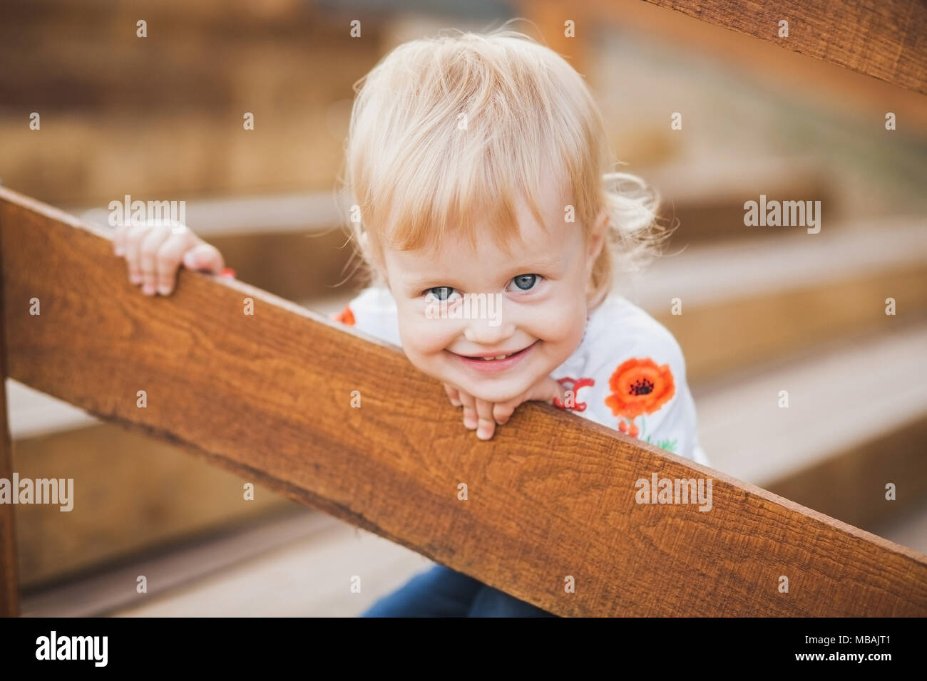 1 Jahr alt wenig caucasiangirl palaing verstecken und Spiel im Freien auf sonnigen warmen Sommertag suchen. Closeup Portrait von tricky Gesicht des blonden Baby versteckt sich fr Stockfoto