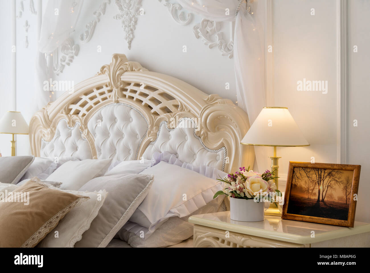 Komfortable Zimmer im klassischen Schlafzimmer mit Lampe und Bild auf dem Nachttisch Stockfoto