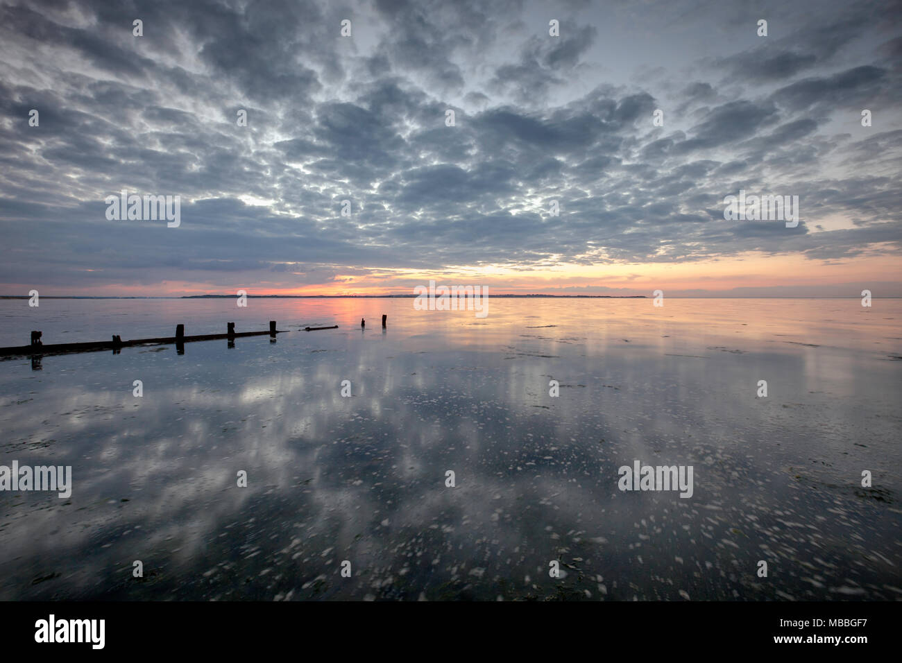 Schönen Sonnenuntergang am Seasalter, Whitstable, Kent, Großbritannien. Seasalter hat einen Kiesstrand und eine Reihe von Holz- buhnen. Die Ansicht ist von der Insel Sheppey. Stockfoto