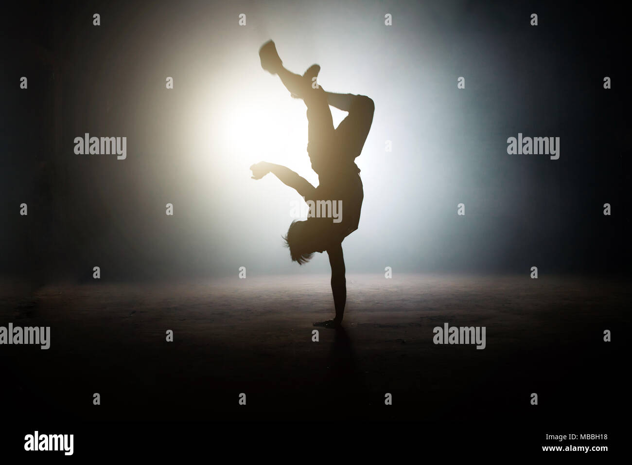 Menschen, die einen einhändigen Handstand mit Beinen auf der hellen Bühne Stockfoto
