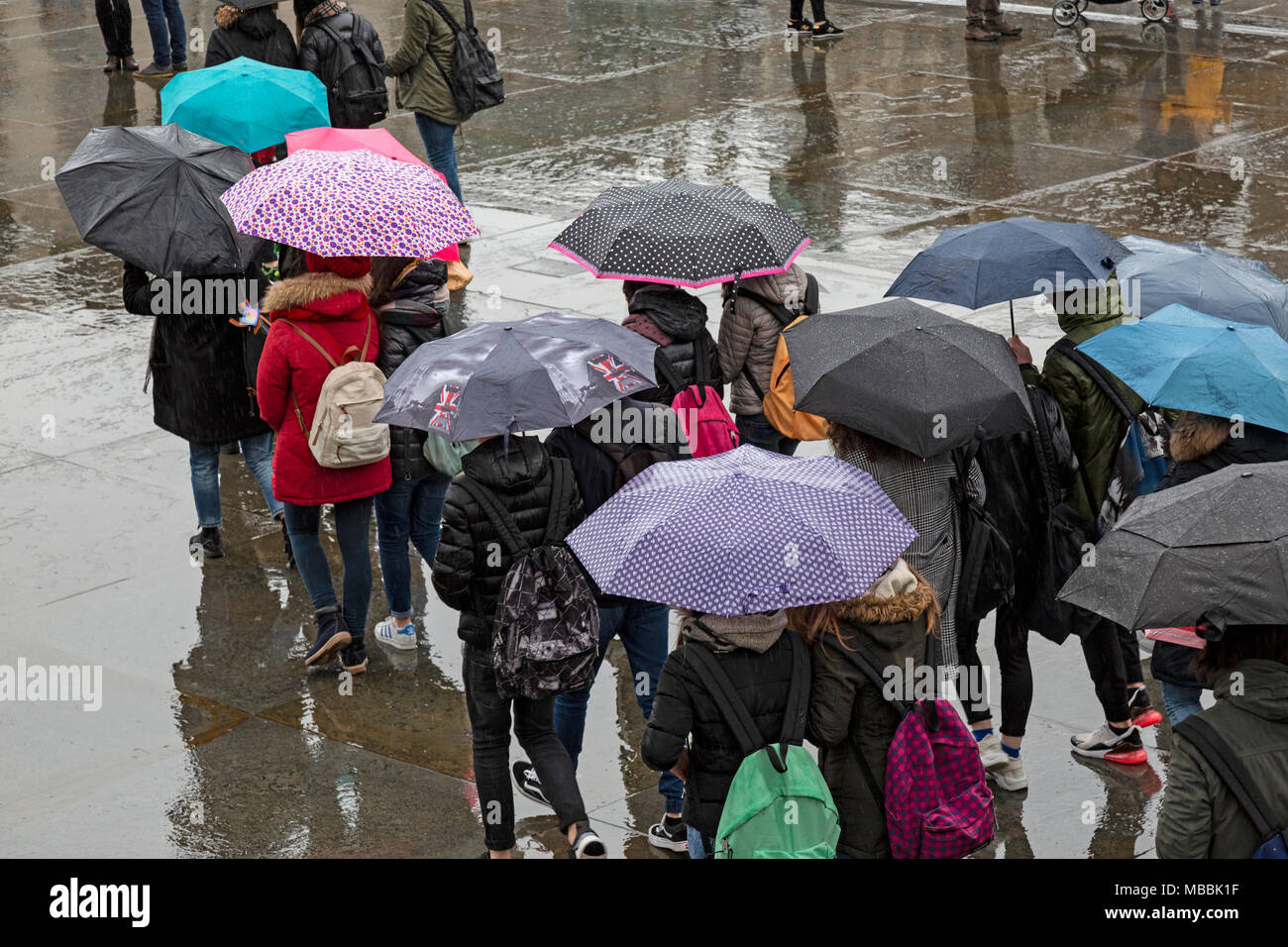 Touristen auf dem Trafalgar Square, London, Sonnenschirme, die zum Schutz vor dem Regen. Stockfoto