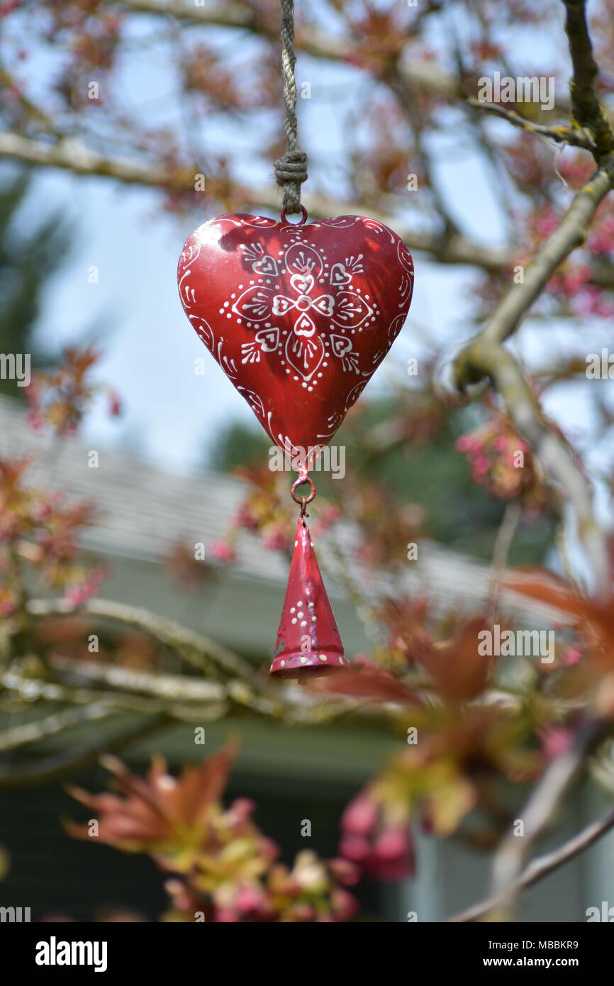 Ein Herz Glocke hängen in einem Apfelbaum Stockfoto