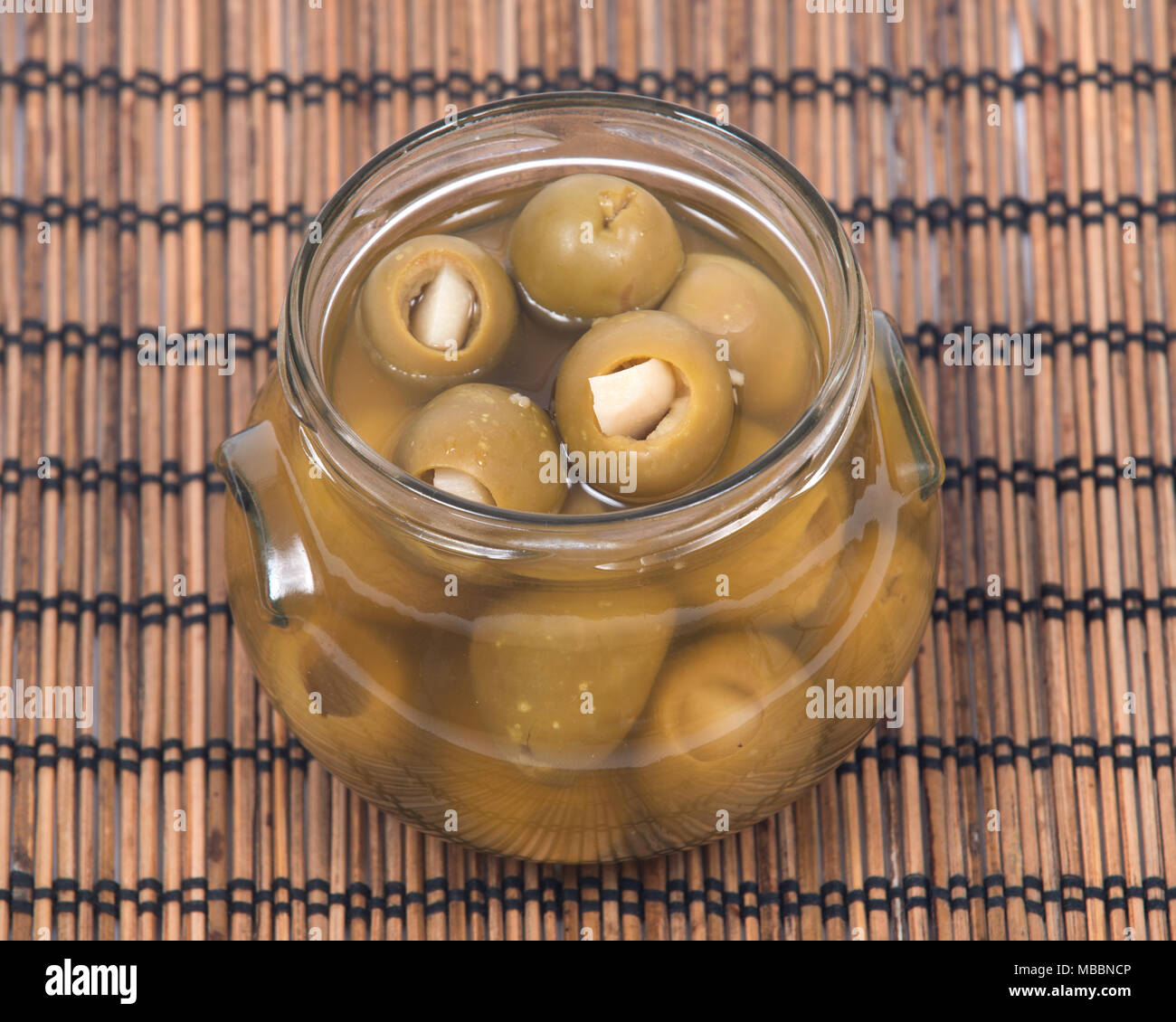 Grüne kolossale Oliven gefüllt mit Knoblauch Handschuhe Hand in den jar Stockfoto