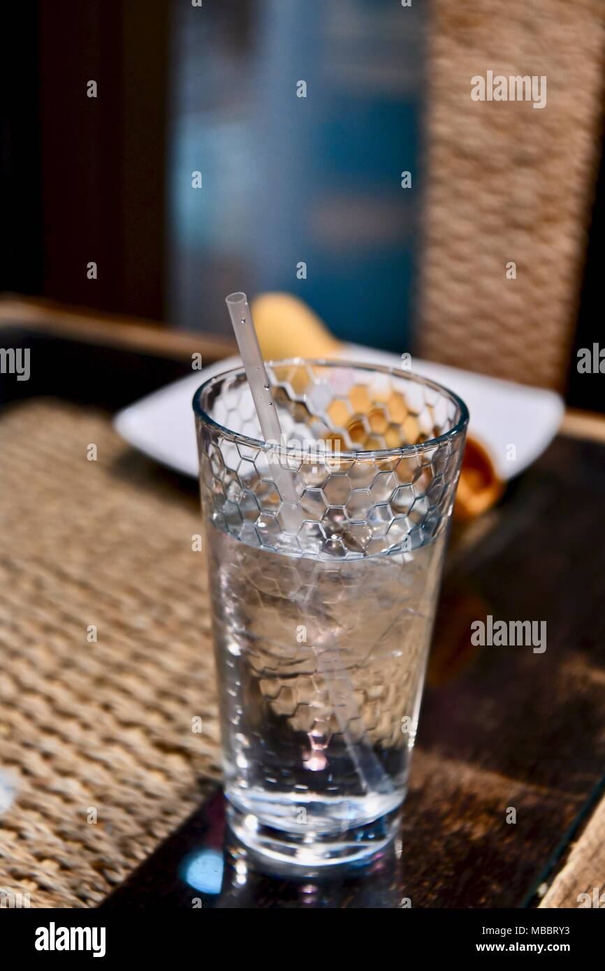 Glas Wasser mit Strohhalm auf einem Tisch im Restaurant Stockfoto