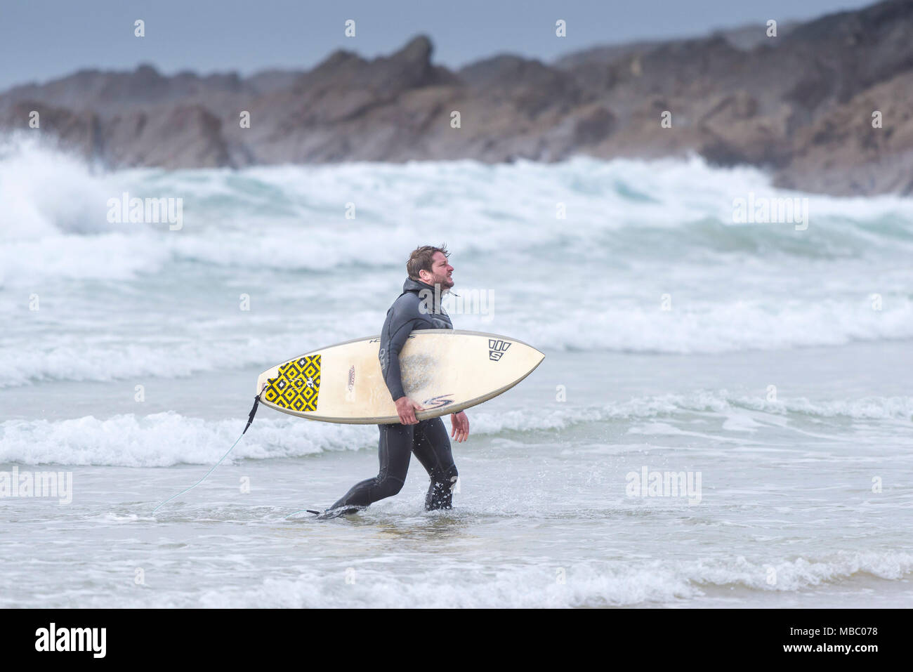Ein Surfer zu Fuß aus dem Meer sein Surfbrett; Stockfoto