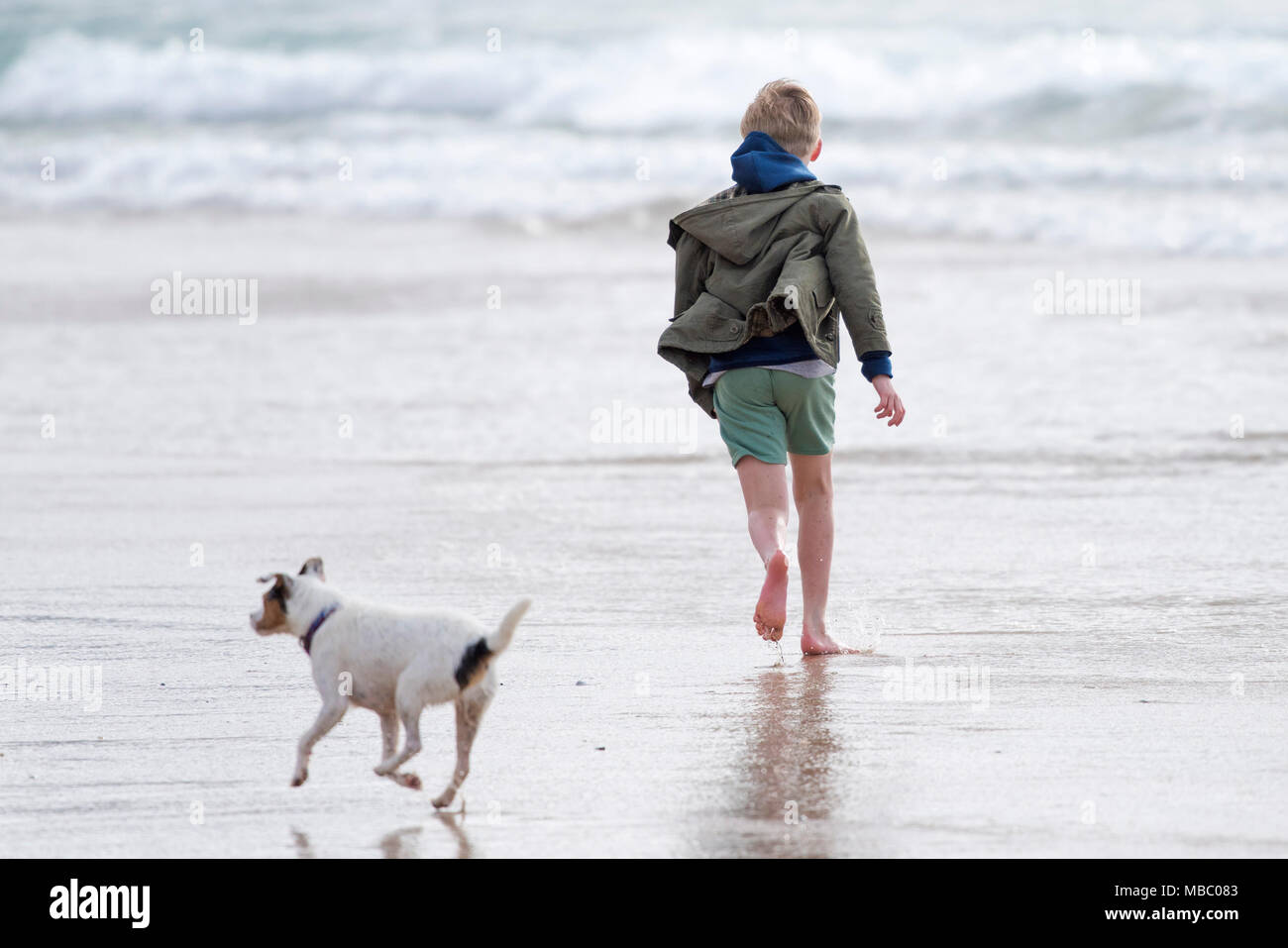 Ein Junge und sein Hund läuft auf einem Strand. Stockfoto