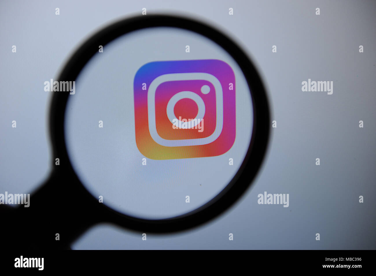 Die Instagram Logo durch eine magnifiying Glas gesehen Stockfoto