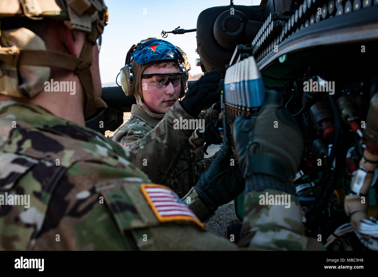 Spc. Jason Offutt (Mitte), eine AH-64 Hubschrauber Systeme Werkstatt, an Unternehmen vergeben, 1.BATAILLON, 227 Aviation Regiment, 1 Air Cavalry Brigade, Fort Hood, Texas, lädt eine AH-64 Apache Helikopter mit Munition vor Beginn der live-Fire Training Februar 16, 2018 bei Novo Selo, Bulgarien. (U.S. Armee Stockfoto