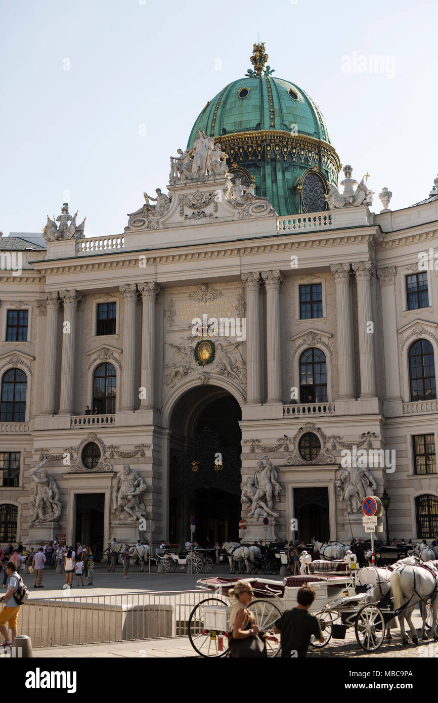 Touristen sammeln und Pferdekutschen warten auf Kunden in der Hofburg am Michaelerplatz in Wien, Österreich. Stockfoto