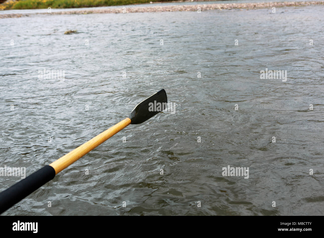 Nahaufnahme eines oar über der Oberfläche des Wassers erhöht während einer rudern Strich von einem kleinen Boot auf einem Fluss oder See gesehen Stockfoto