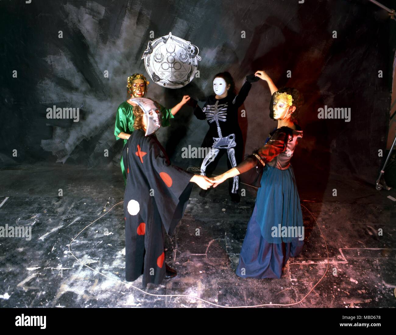 Gruppe von Menschen, die in einer schwarz-Magie/Hexerei burleske, ausgefallene Kostüme und Masken, Tanzen in einem magischen Kreis. - ©/Charles Walker Stockfoto