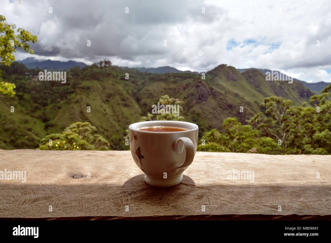 Ein Glas heißen Tee auf dem Tisch im Tee Shop und Blick auf kleine Dämme Peak in Sri Lanka. Stockfoto